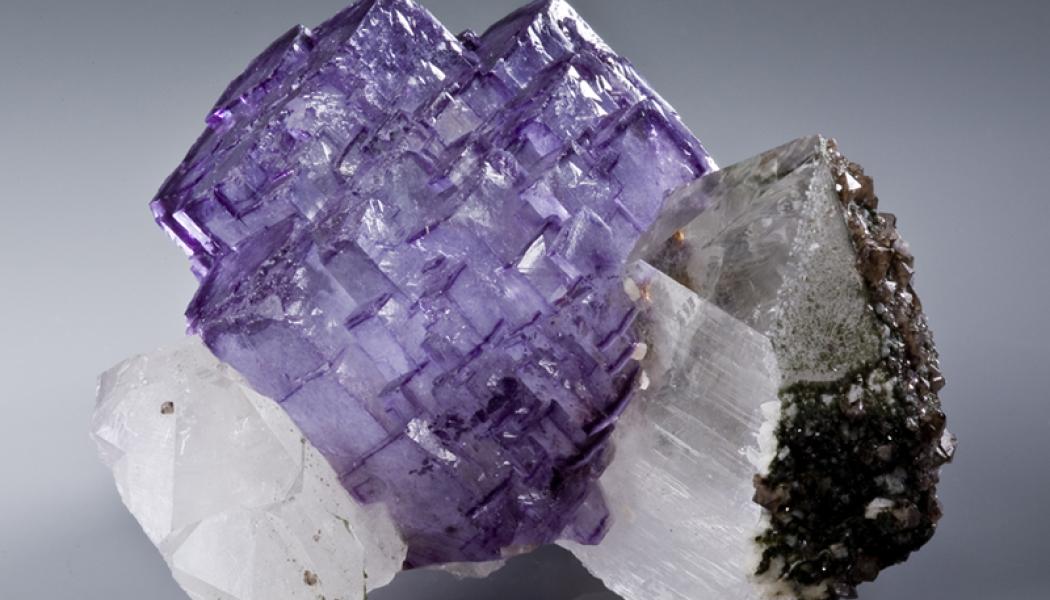 Freestanding purple fluorite cluster between two quartzes. Photo: Rob Lavinsky, iRocks.com/Wikimedia Commons