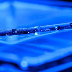 Metal treated with micro- and nanostructures can float on water, even after being drilled with holes. Foto: The University of Rochester