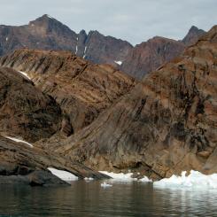 View of the Skaergaard layered igneous intrusion (a series of plutonic rocks inclined from upper left to lower right) in East Greenland, showing the Middle Zone from Kraemer Ø with Wager Top in the centre of the background.
Photo: C. Tegner - Cover photo from Thy, P.; Tegner, C.; Lesher, C.E. (2023) "Petrology of the Skaergaard Layered Series", GEUS Bulletin 56, https://doi.org/10.34194/geusb.v56.832,(https://geusbulletin.org/index.php/geusb/issue/view/1139)/Wikimedia Commons